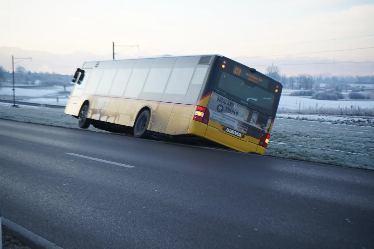 Ein gelber Postautobus ist von der Strasse abgekommen und steht in einer Wiese.